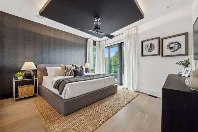 bedroom featuring access to exterior, light wood-type flooring, visible vents, and baseboards