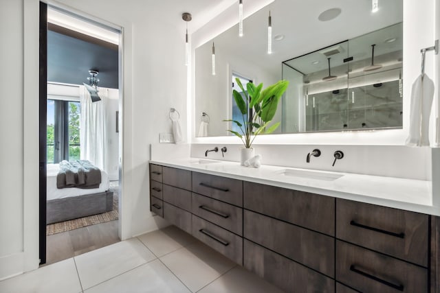 bathroom with double vanity, ensuite bathroom, tile patterned floors, a shower stall, and a sink