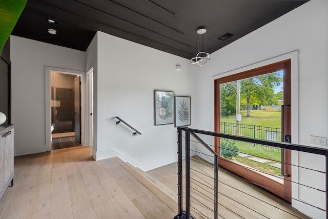 stairs with a notable chandelier, wood-type flooring, visible vents, and baseboards