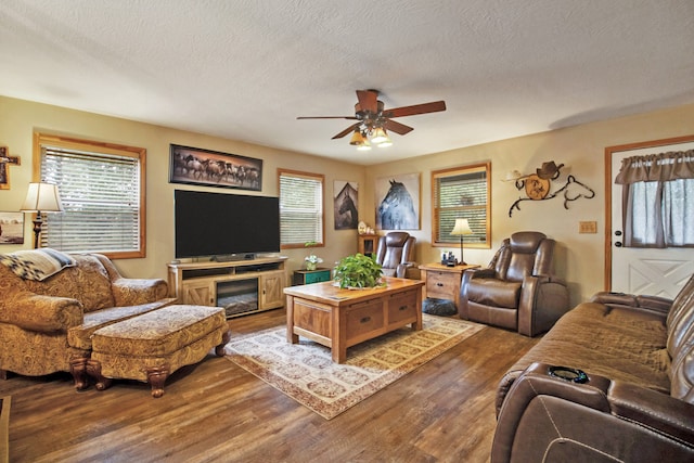 living room featuring ceiling fan, a textured ceiling, and dark hardwood / wood-style floors