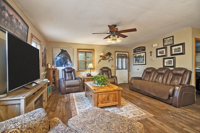 living room featuring ceiling fan, a textured ceiling, and dark wood-type flooring