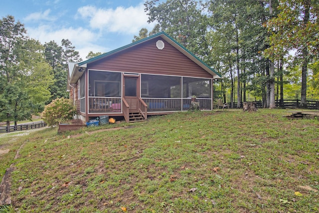 rear view of property featuring a sunroom and a lawn