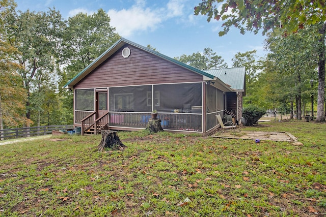 rear view of house featuring a sunroom and a lawn