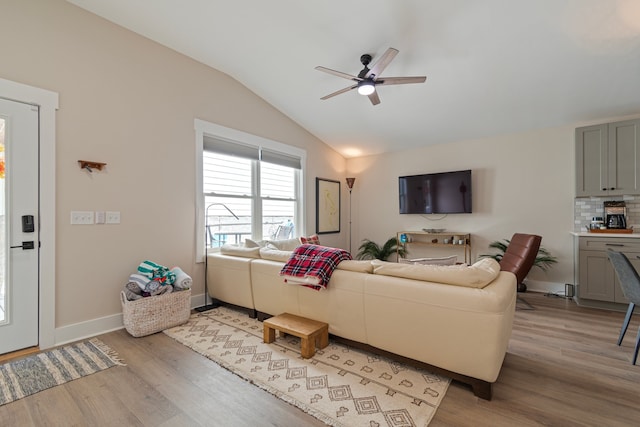 living room with light hardwood / wood-style floors, lofted ceiling, and ceiling fan