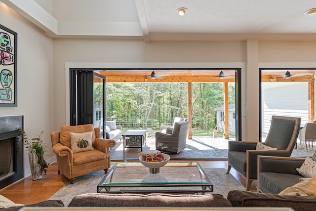 living room with beamed ceiling, a textured ceiling, hardwood / wood-style flooring, and a healthy amount of sunlight