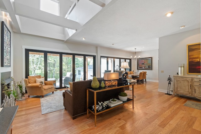 living room with light hardwood / wood-style flooring, a textured ceiling, and an inviting chandelier