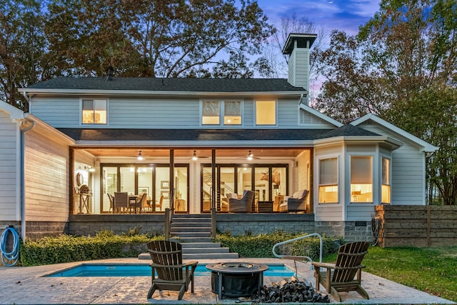 back house at dusk with a patio, ceiling fan, and an outdoor fire pit