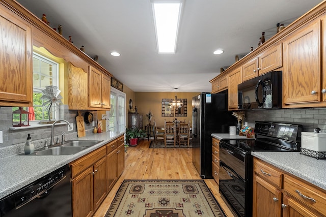 kitchen featuring black appliances, light hardwood / wood-style floors, decorative backsplash, and sink