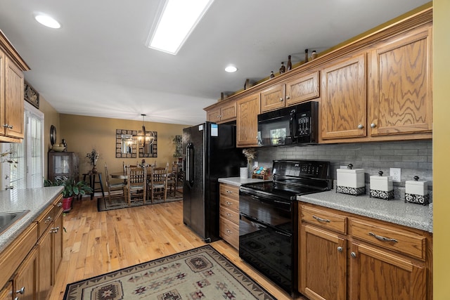 kitchen featuring decorative backsplash, light hardwood / wood-style floors, black appliances, decorative light fixtures, and a chandelier