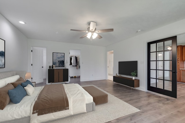 bedroom with a spacious closet, hardwood / wood-style floors, ceiling fan, and a closet