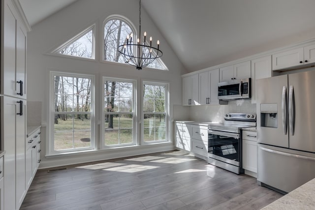 kitchen with white cabinets, a chandelier, stainless steel appliances, and a wealth of natural light