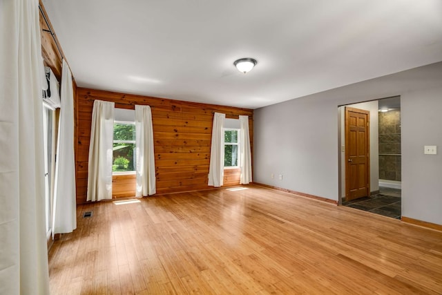 unfurnished room featuring wooden walls and hardwood / wood-style floors