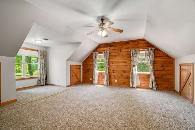 bonus room featuring wooden walls, lofted ceiling, ceiling fan, and carpet floors