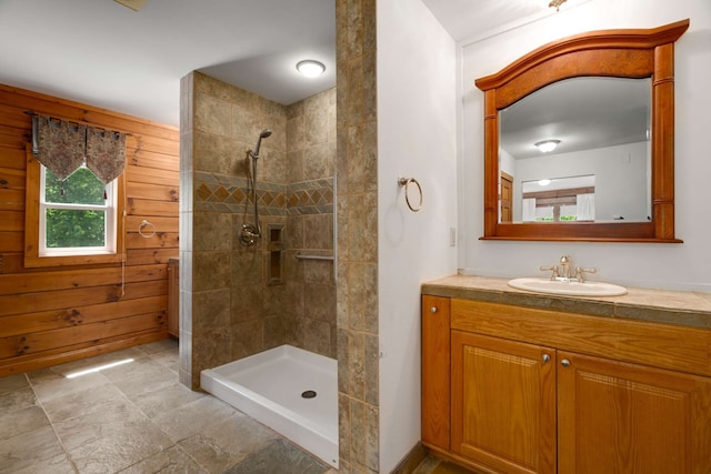 bathroom featuring a tile shower, wooden walls, and vanity