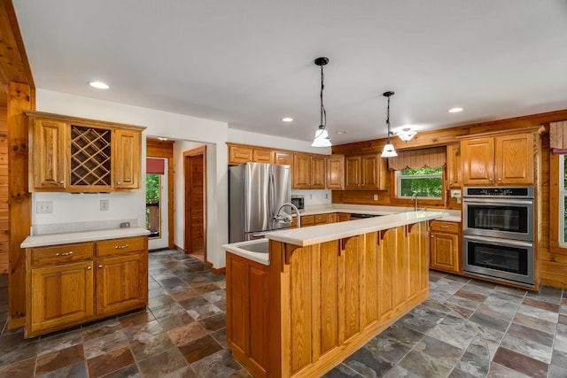 kitchen with an island with sink, pendant lighting, stainless steel appliances, and a breakfast bar