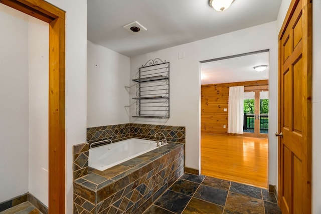 bathroom with wood-type flooring and tiled bath