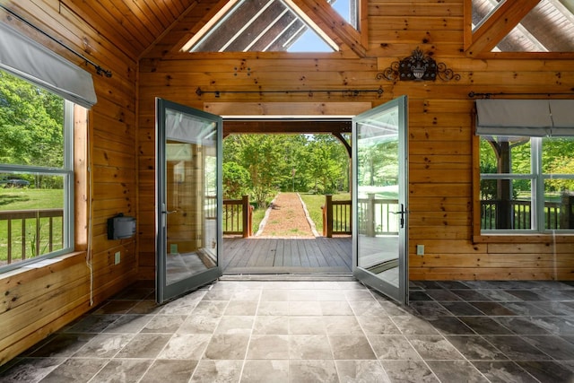 doorway with a skylight, wood ceiling, wood walls, and high vaulted ceiling