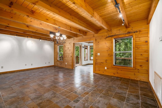 spare room featuring rail lighting, wood walls, beamed ceiling, wooden ceiling, and a chandelier