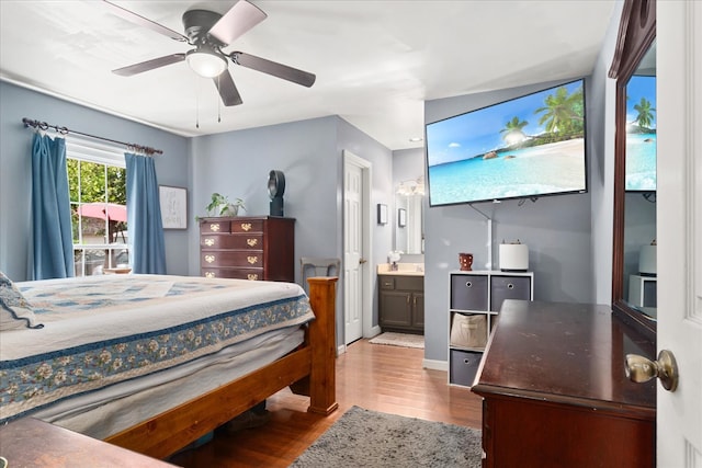 bedroom featuring ceiling fan, light hardwood / wood-style flooring, and connected bathroom