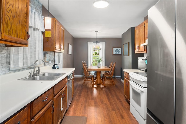 kitchen featuring dark hardwood / wood-style floors, sink, stainless steel appliances, exhaust hood, and decorative light fixtures