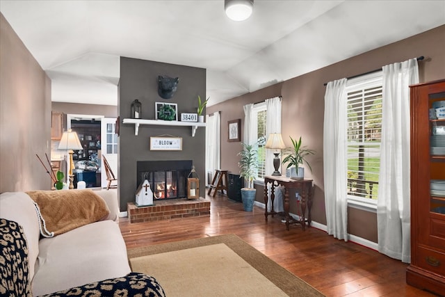 living room featuring wood-type flooring, a fireplace, and vaulted ceiling