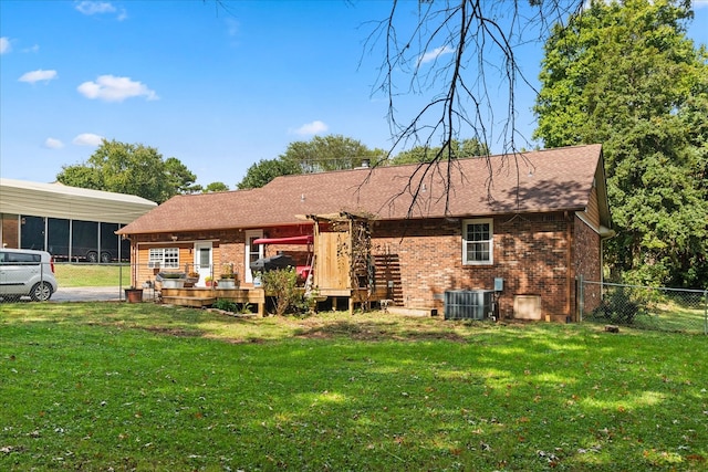 rear view of property with a lawn, a carport, a wooden deck, and central AC unit