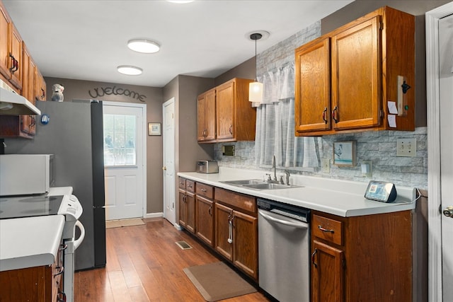 kitchen with dark wood-type flooring, sink, stove, decorative light fixtures, and stainless steel dishwasher