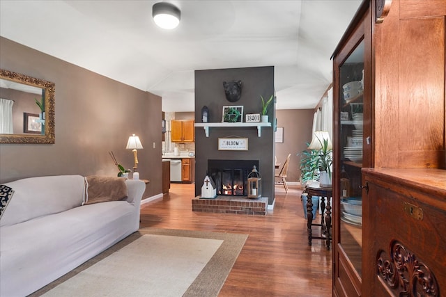 living room featuring a brick fireplace, lofted ceiling, and hardwood / wood-style floors