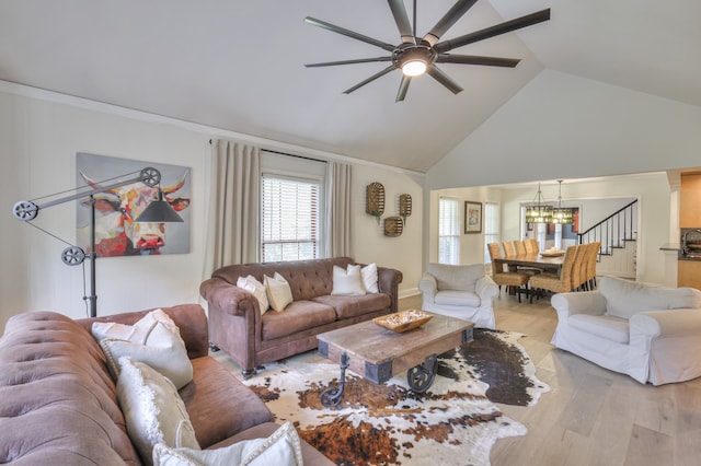 living room featuring ceiling fan with notable chandelier, high vaulted ceiling, and light hardwood / wood-style flooring