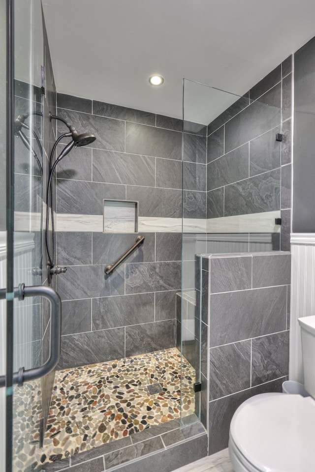 bathroom featuring toilet and a shower with door