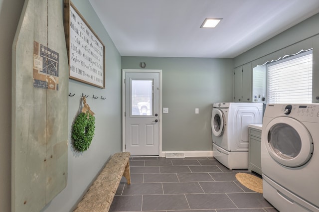 laundry room with separate washer and dryer, dark tile patterned floors, and cabinets