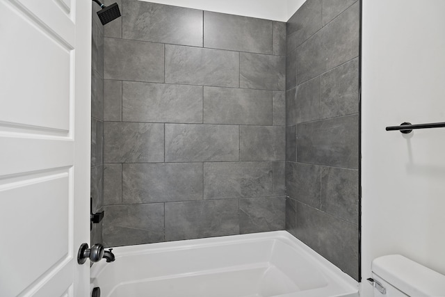 bathroom featuring tiled shower / bath combo and toilet