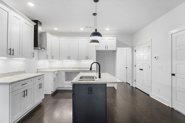 kitchen with white cabinets, sink, decorative light fixtures, a kitchen island with sink, and wall chimney exhaust hood