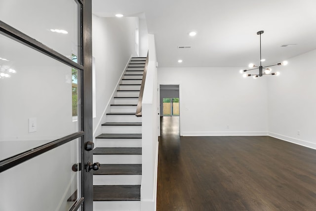 stairway with a notable chandelier and hardwood / wood-style flooring