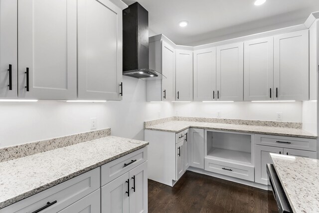 kitchen featuring white cabinets, light stone countertops, dark wood-type flooring, and wall chimney range hood