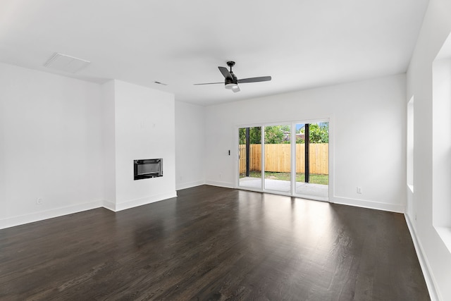 unfurnished living room featuring ceiling fan, heating unit, and dark hardwood / wood-style flooring