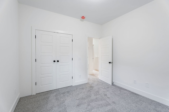 unfurnished bedroom with light colored carpet and a closet