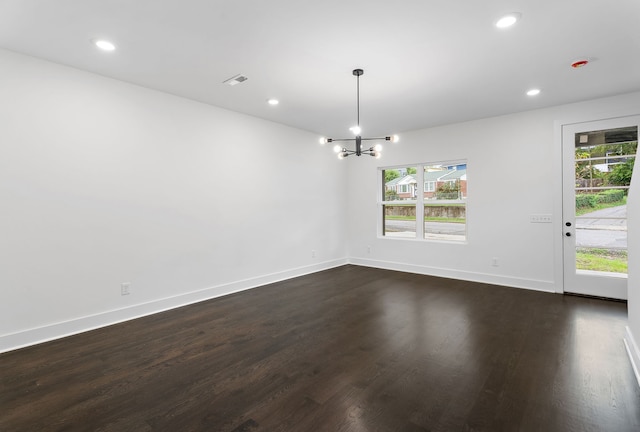 empty room featuring an inviting chandelier and dark hardwood / wood-style floors