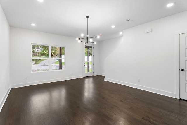 unfurnished room featuring an inviting chandelier and dark hardwood / wood-style floors