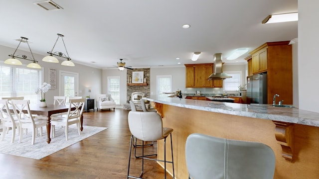 kitchen with stainless steel fridge, kitchen peninsula, ceiling fan, and island range hood