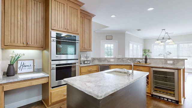 kitchen featuring appliances with stainless steel finishes, a center island with sink, wine cooler, and decorative light fixtures