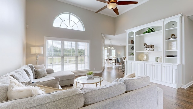 living room with a towering ceiling, dark hardwood / wood-style flooring, ceiling fan, and plenty of natural light