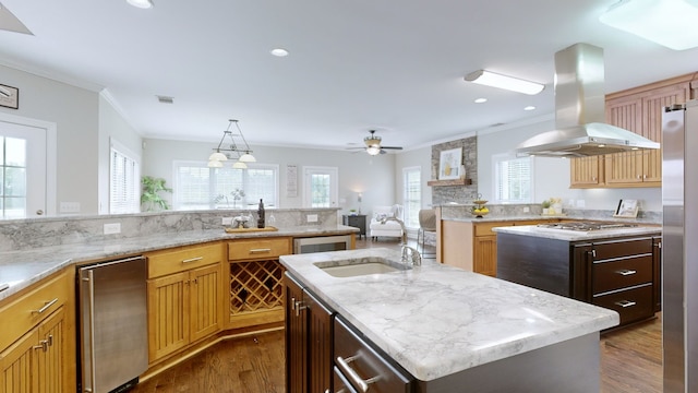 kitchen featuring appliances with stainless steel finishes, island range hood, dark hardwood / wood-style flooring, ceiling fan, and a kitchen island with sink