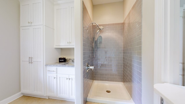 bathroom with vanity, tile patterned flooring, and a tile shower