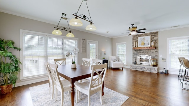 dining space featuring crown molding, a fireplace, dark hardwood / wood-style flooring, and ceiling fan