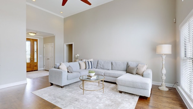 living room with ornamental molding, a towering ceiling, ceiling fan, and dark hardwood / wood-style flooring