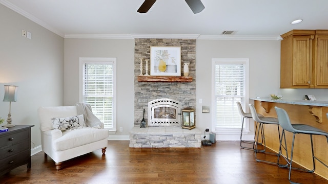 living area featuring ceiling fan, a fireplace, dark hardwood / wood-style floors, and crown molding