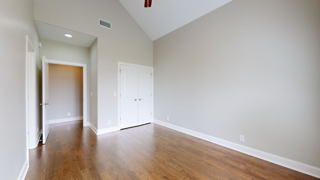 unfurnished bedroom with high vaulted ceiling, a closet, and dark hardwood / wood-style flooring