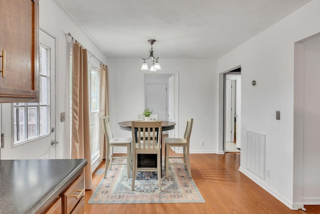 dining room with an inviting chandelier, a healthy amount of sunlight, and light hardwood / wood-style flooring