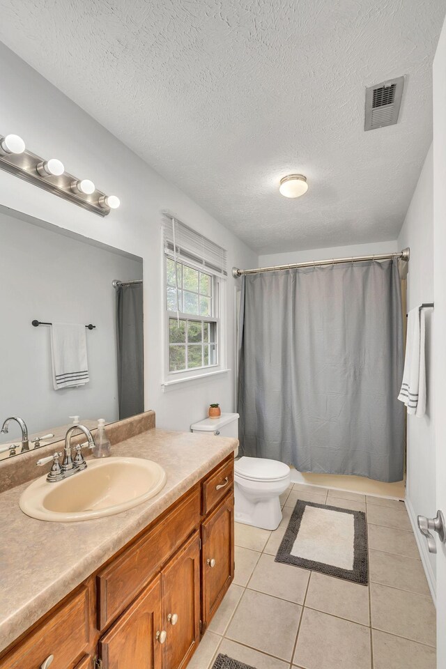 bathroom featuring vanity, tile patterned flooring, a textured ceiling, and toilet